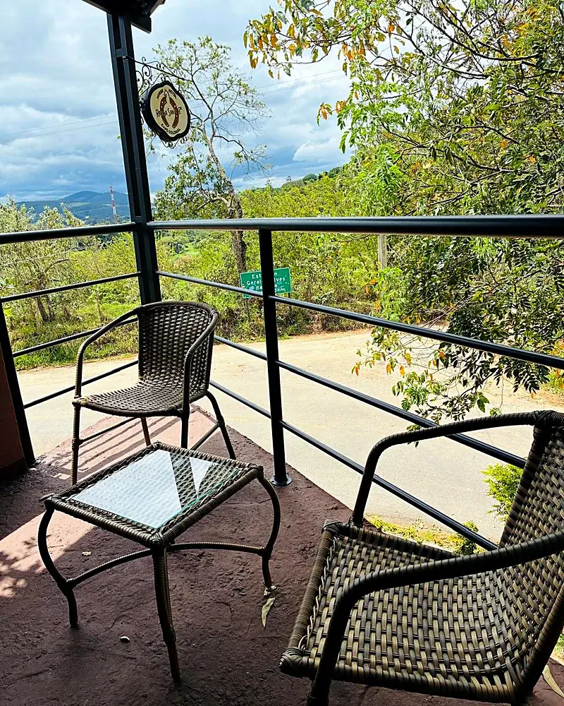 Varanda com cadeiras de vime e vista para o vale, com a placa do Rancho Santa Fé pendurada